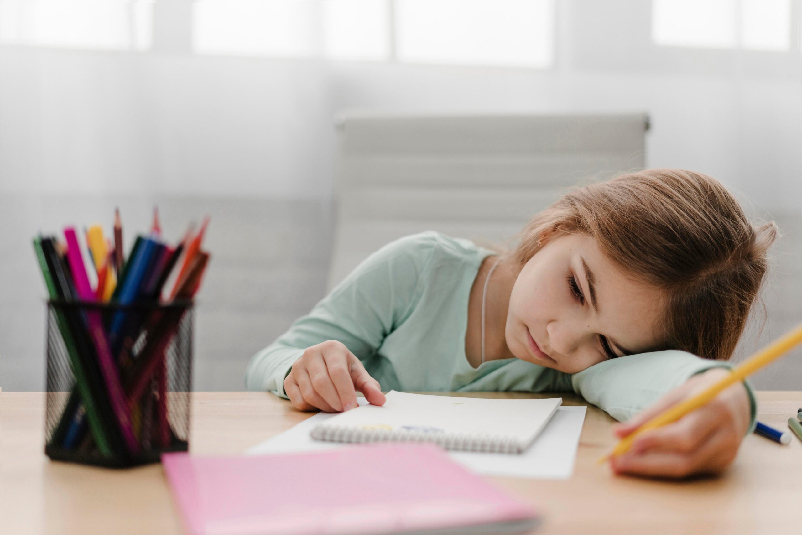 bored little girl taking notes while having online class 1 scaled