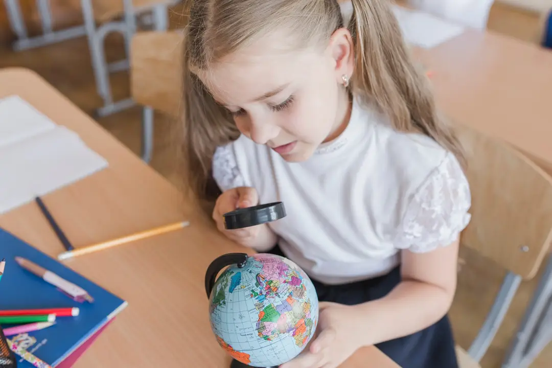 girl examining globe with magnifying glass 1 scaled