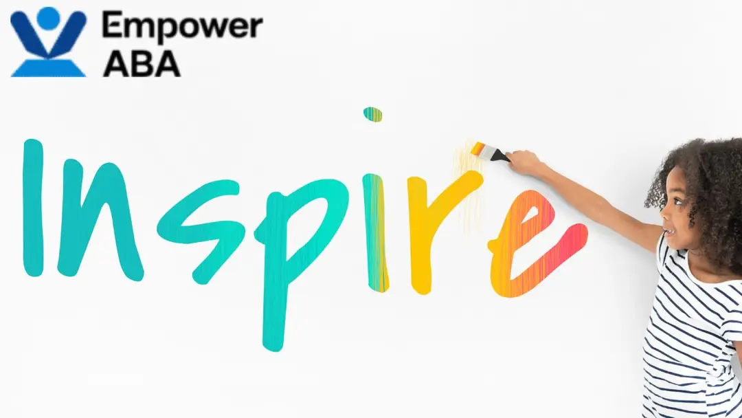 Quotes autism awareness: a young girl stands beside and points at a large wall illustration of the word “inspire.”