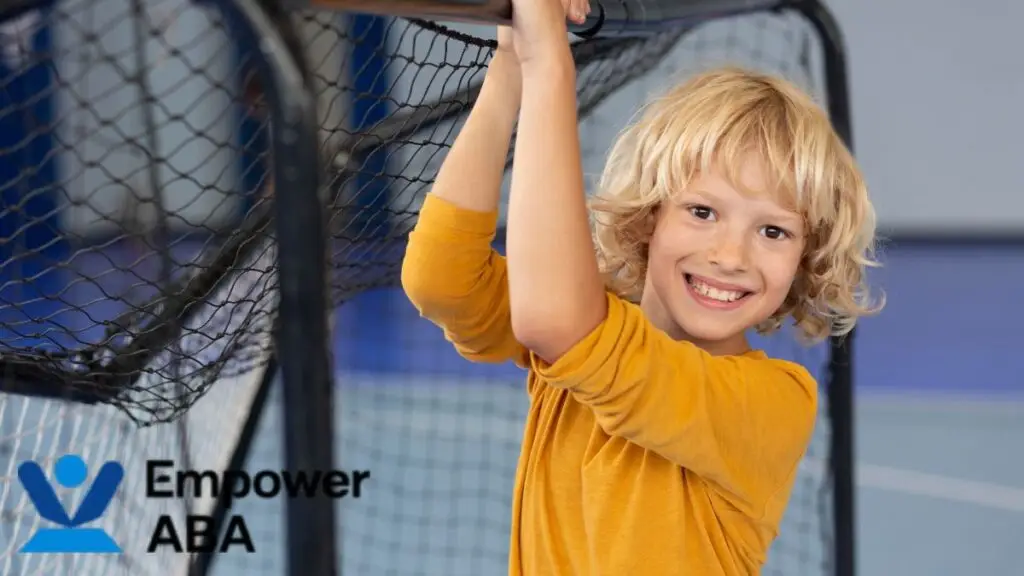 Sensory integration therapy autism: A young boy smiles for the camera while completing a heavy work activity using a net, building strength and focus through play.