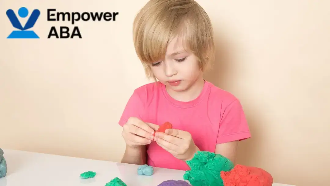 Play schemas autism, a young child in a pink shirt molds pieces of clay.