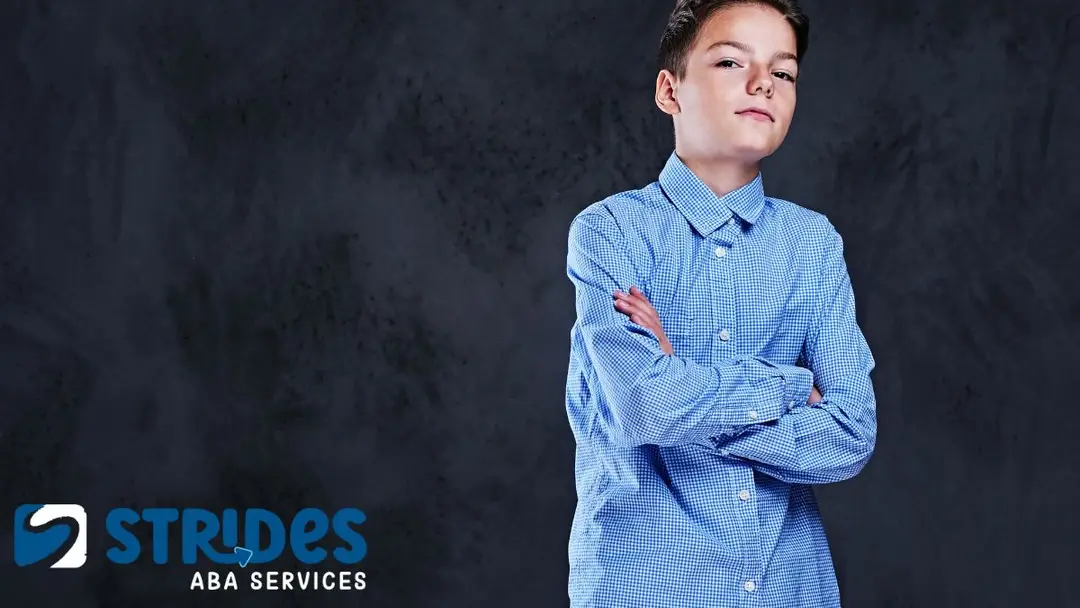 How to deal with overstimulation autism: a lone boy in a powder blue long-sleeved shirt crosses his arms, appearing to self-soothe.
