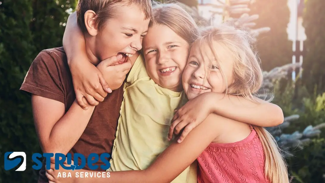 How to deal with overstimulation autism: a group of three children embrace each other in a sunlit meadow, warm sunshine touching them.