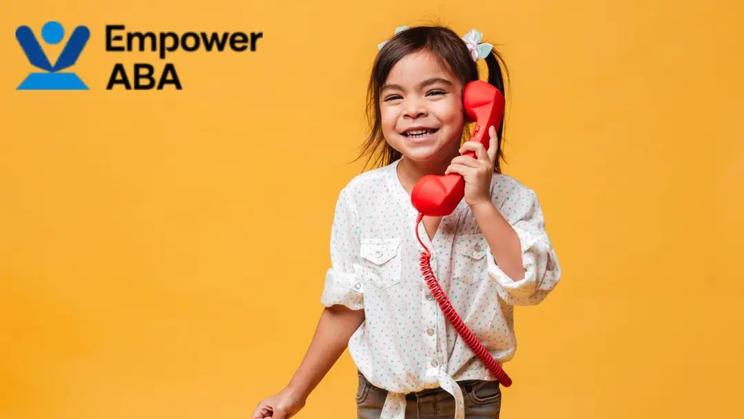 Smiling young girl confidently talking on a vintage red phone, symbolizing how autism affects communication and brain function.