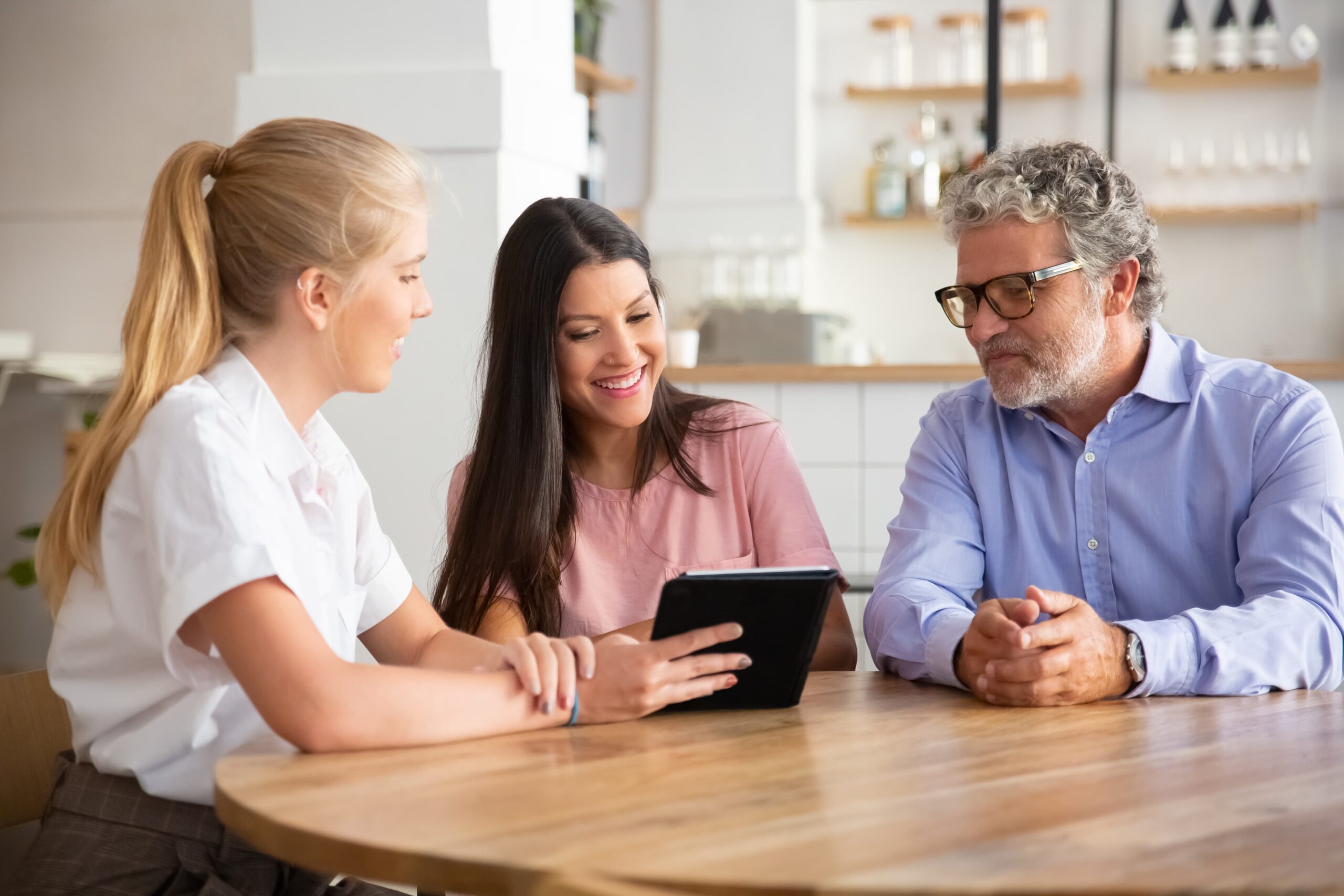 female agent manager meeting with couple young mature customers presenting content tablet 1 scaled