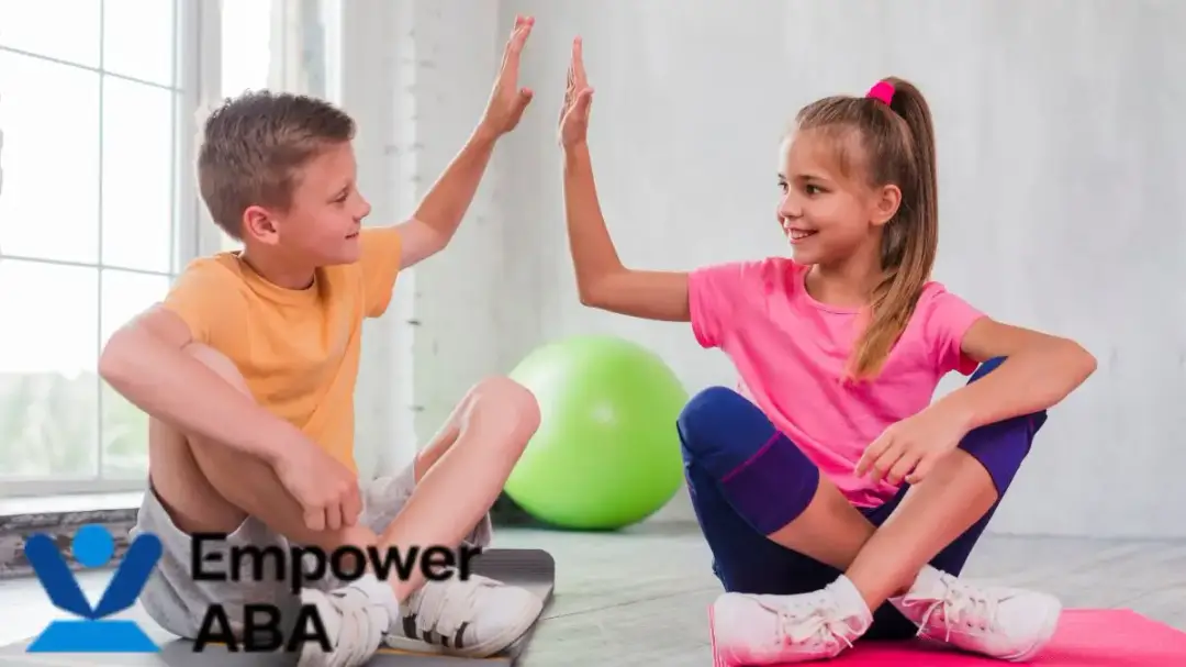 Autism vestibular therapy: two children high-five on the floor amid therapy equipment.